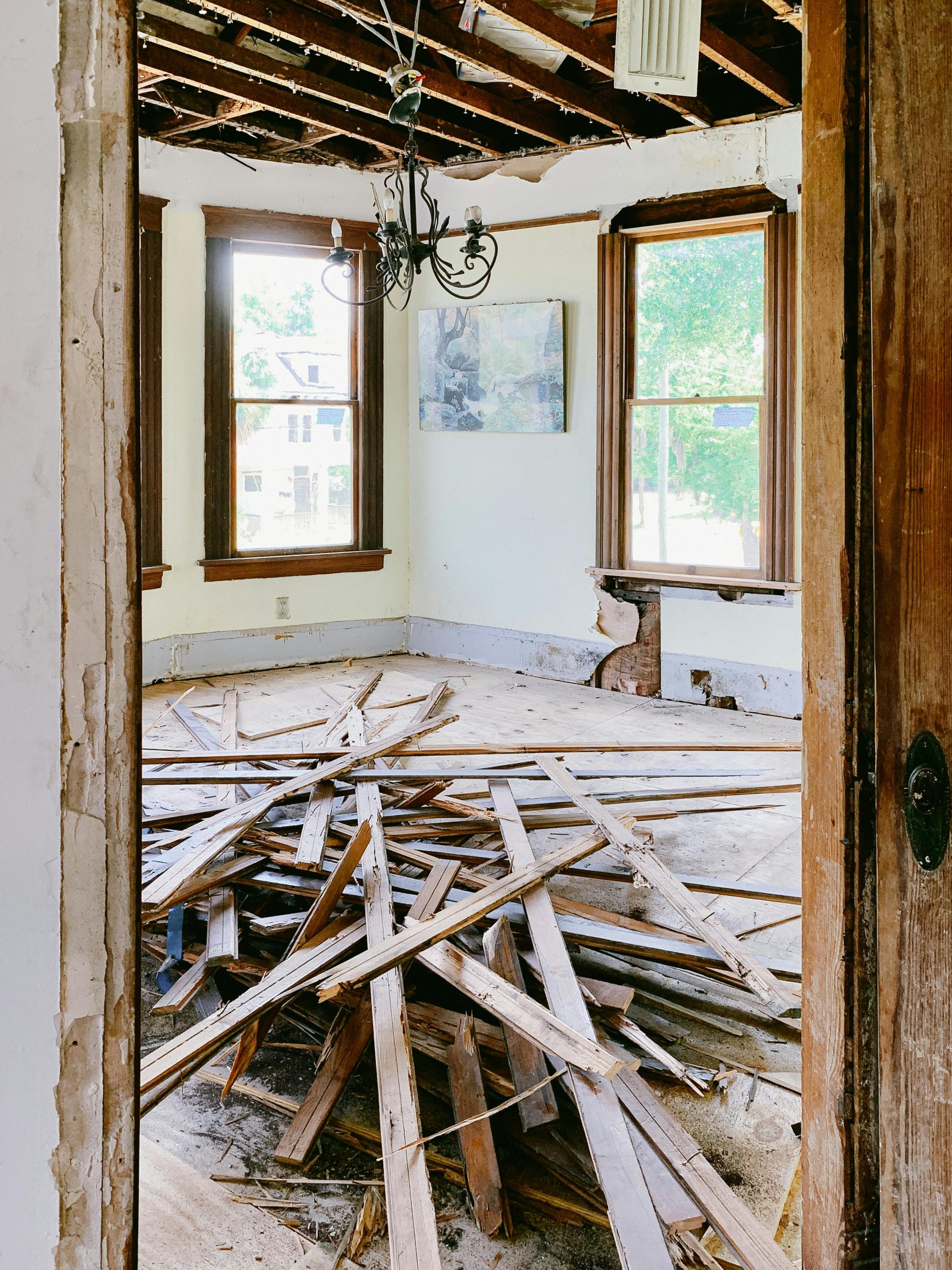 Interior room under renovation with exposed beams and planks piled on the floor.