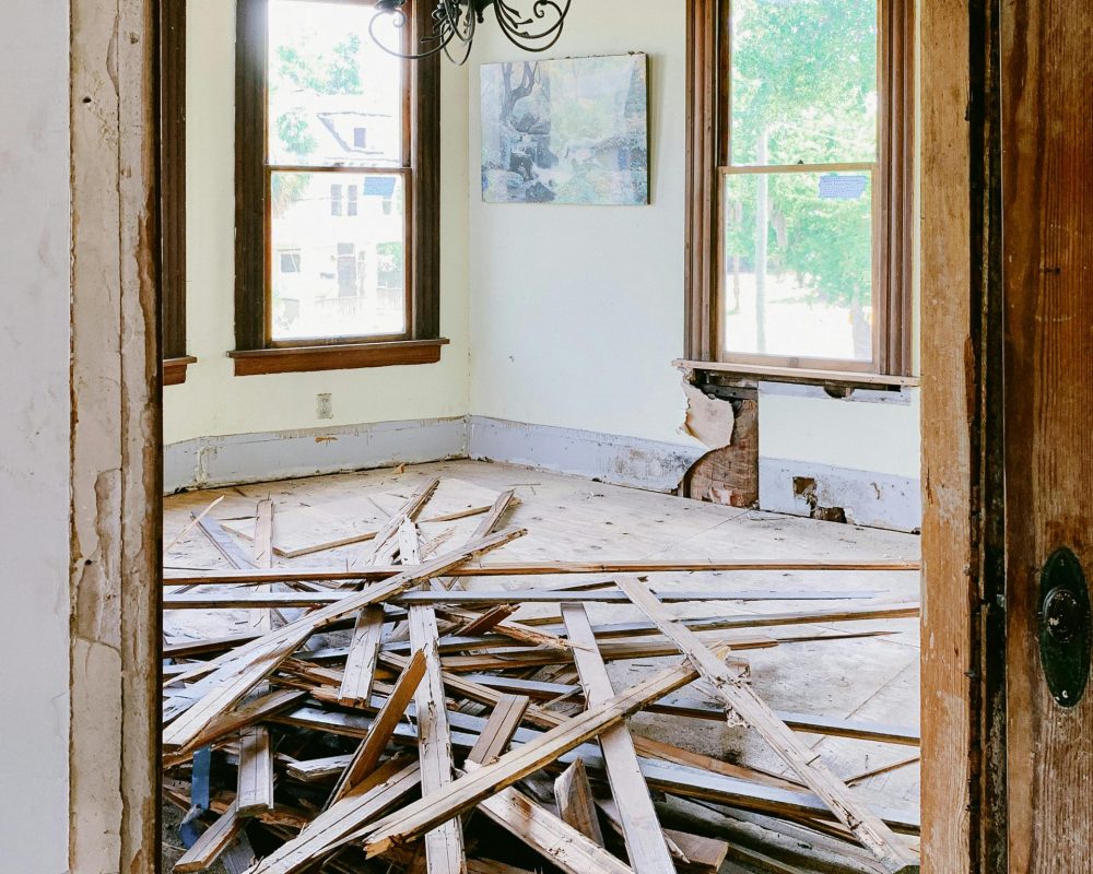 Interior room under renovation with exposed beams and planks piled on the floor.