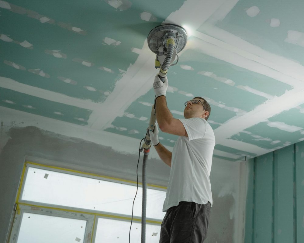 A professional worker sanding the ceiling during a home renovation project. Indoor construction setting.